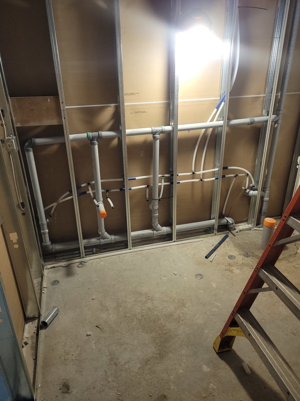 Water supply and drain lines roughed in through steel stud framing on a Brantford job site