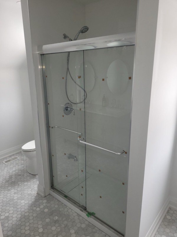 Finished walk-in shower with sliding glass doors and hexagonal mosaic tile floor