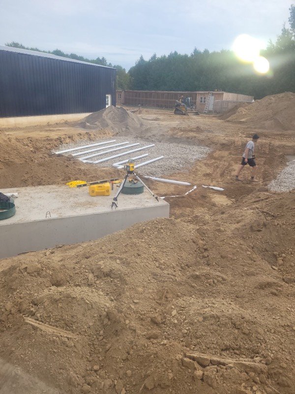 Large site excavation with an underground concrete tank and service lines being set in place