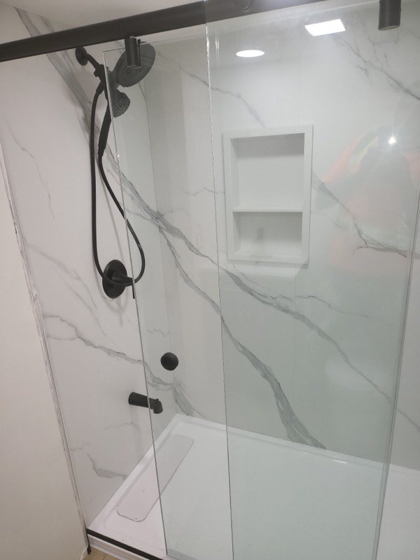 Finished walk-in shower with large-format marble-effect tile, a recessed niche and matte black fixtures