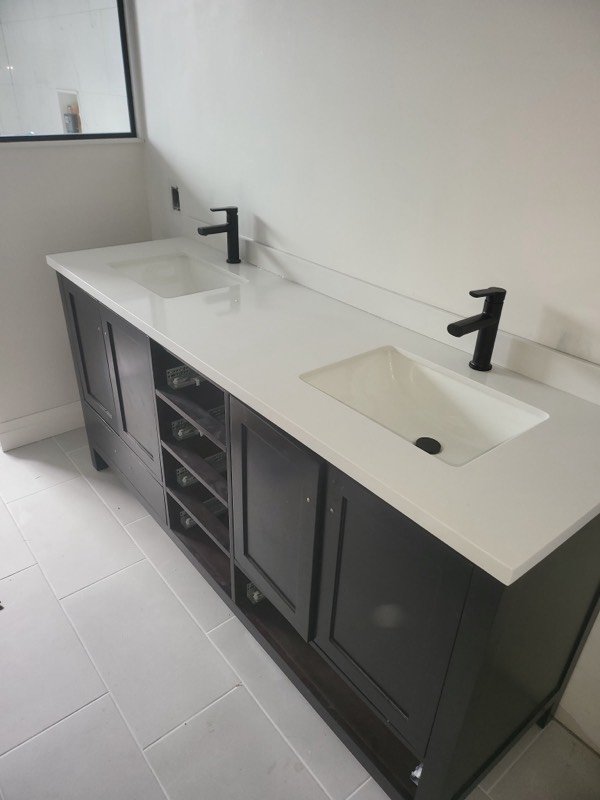 Dark grey double vanity with quartz counter, undermount basins and matte black faucets