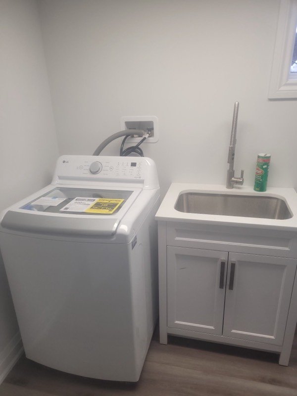 Finished laundry room with a new laundry tub, faucet and connected washing machine