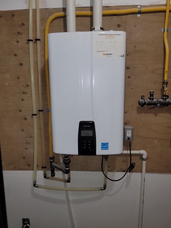 Wall-mounted tankless water heater with gas and water lines connected in a Brantford basement