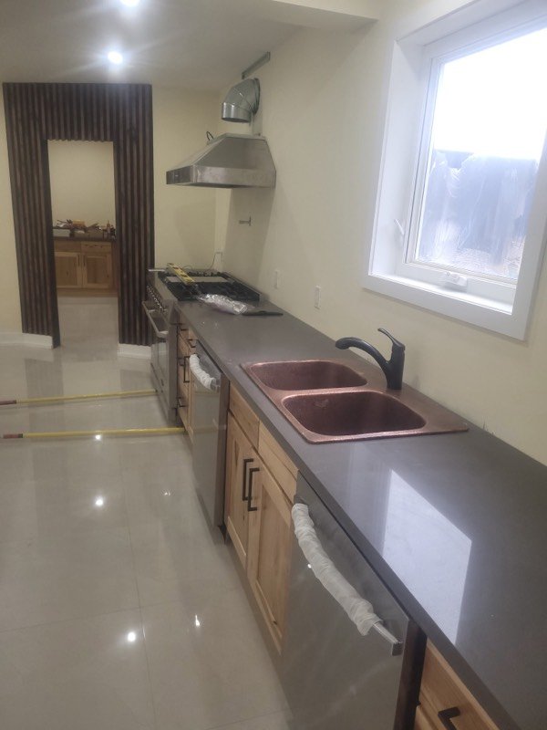 Finished kitchen with a copper-toned undermount sink and black pull-down faucet set in a new counter