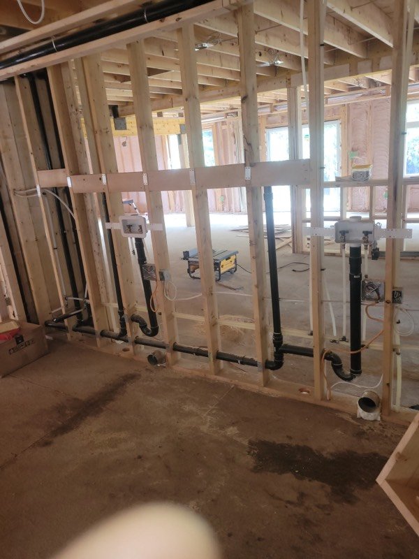 Basement rough-in with drain and supply lines run through framing beside the water meter and main valves