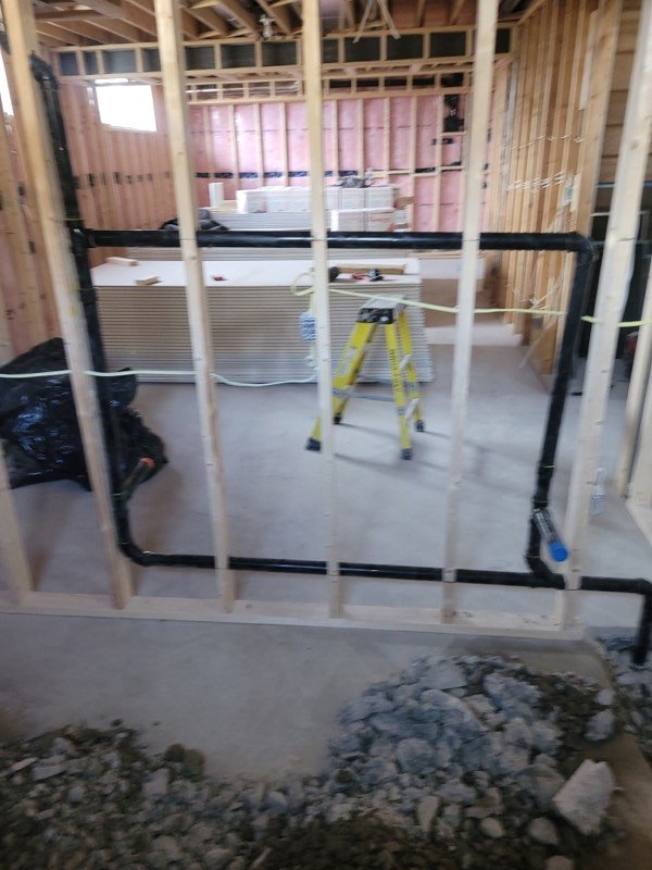 Basement bathroom rough-in with insulated framing and black ABS drain lines run to a new stack